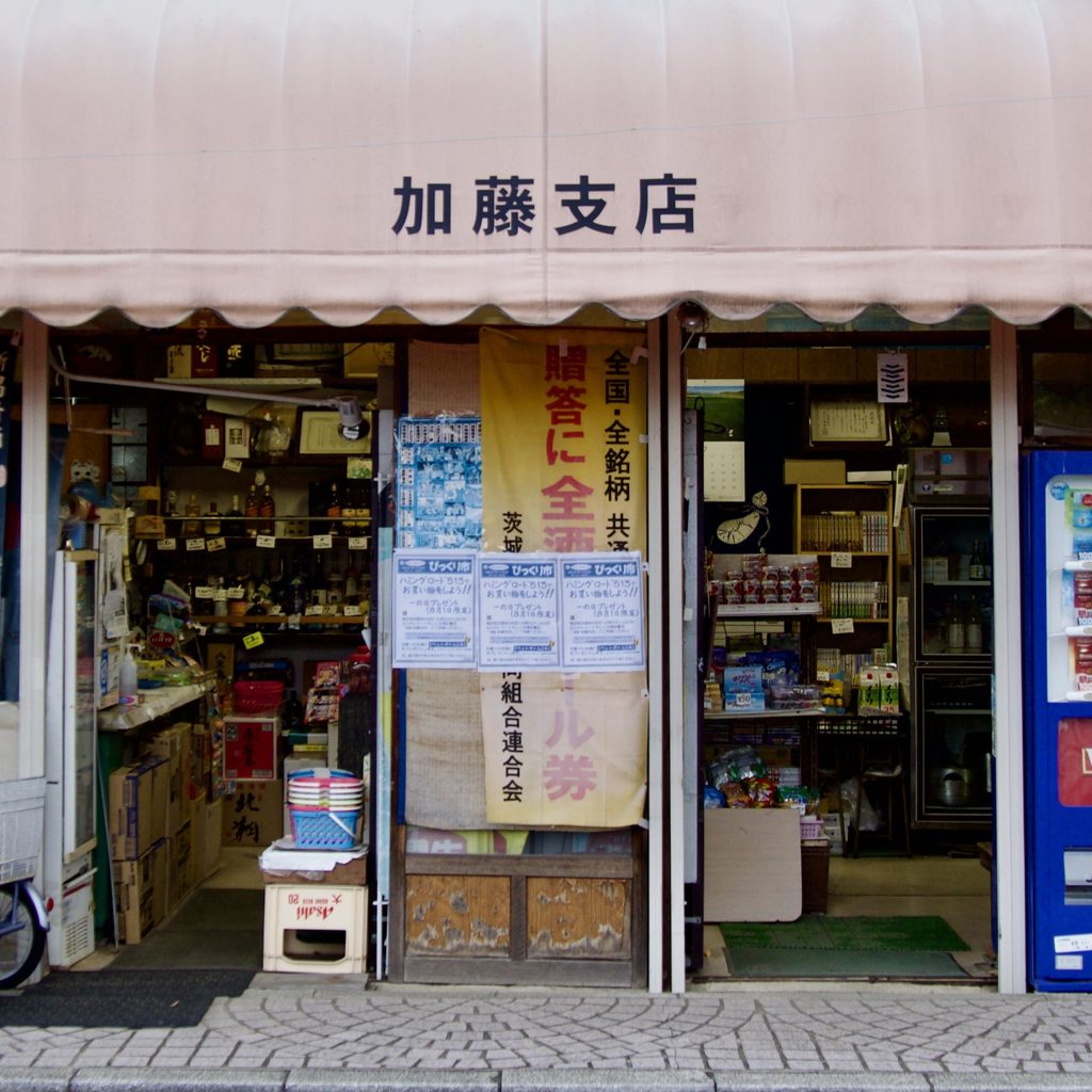 日よけテントに「加藤支店」と書かれた商店の店先