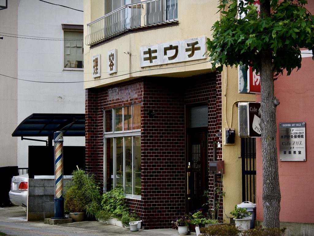 サインポールが立つ理容店「キウチ」のレンガ張りの店構え