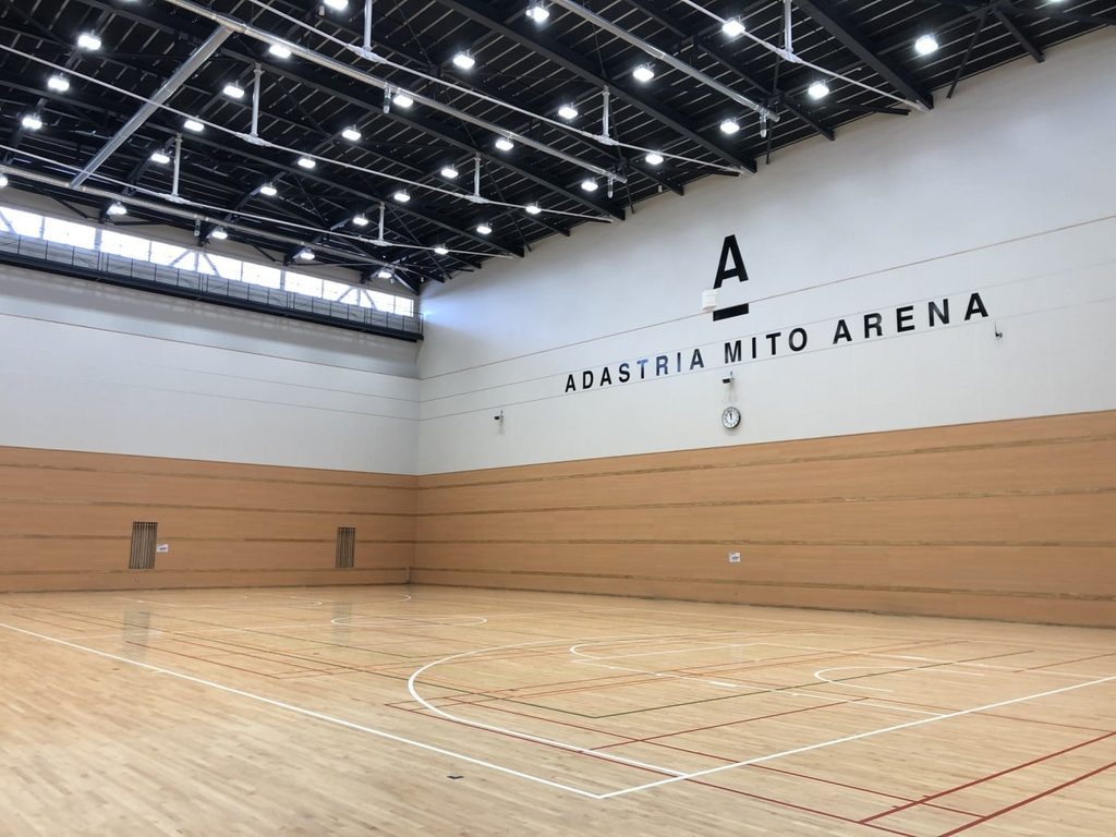 壁にADASTRIA MITO ARENAの文字が掲げられた明るい照明の木製床の体育館