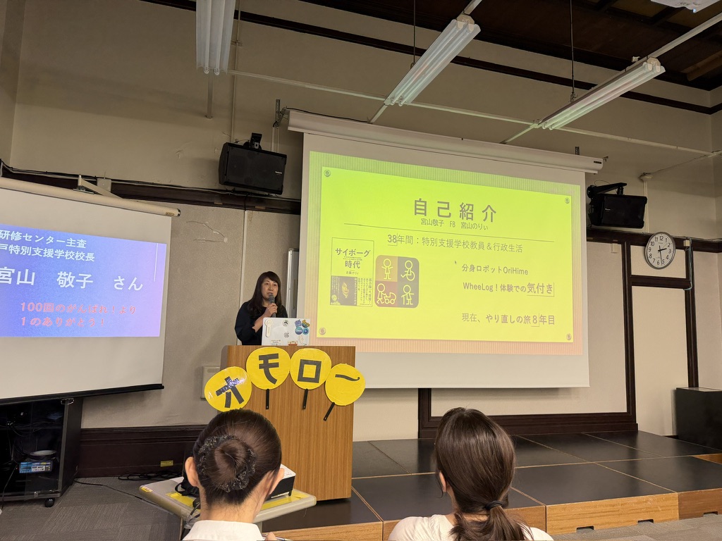 会場のステージで自己紹介のスライドを映しながら話をする宮山敬子さん