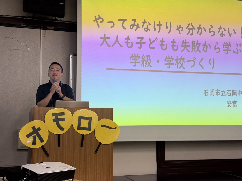 やってみなけりゃ分からない大人も子どもも失敗から学ぶ学級・学校づくりという題名の画面の前で笑顔で話す安富悠介さん