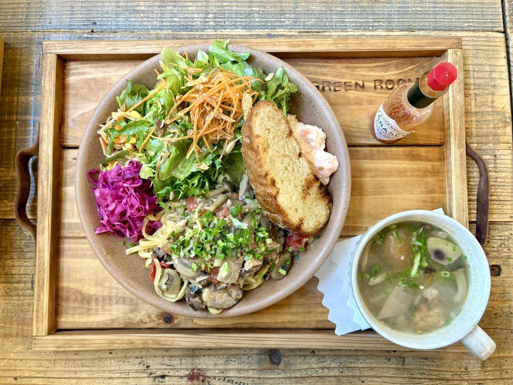 木製のトレイに載ったきのこのパスタと生野菜のサラダとパンとスープのセット